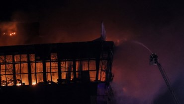 رجال الإطفاء يطفئون الحريق في قاعة الحفلات الموسيقية "كروكوس سيتي هول"، في أعقاب حادث إطلاق النار في كراسنوغورسك، خارج موسكو (22 آذار 2024 - أ ف ب).
