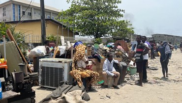 سكان يجلسون بجوار ممتلكاتهم بعد هدم منازلهم في لاغوس (أ ف ب). 