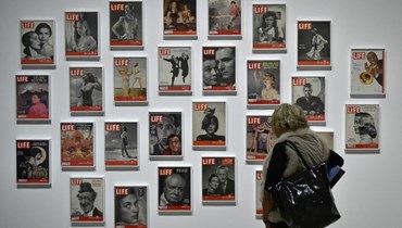  امرأة تنظر إلى الأغلفة الأمامية لمجلات "LIFE" خلال معرض في مدريد (أ ف ب).