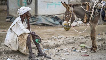 رجل مسن ينتظر إعادة ملء خزان المياه الذي يجره حمار خلال أزمة مياه في بورتسودان في السودان (9 نيسان 2024، أ ف ب). 