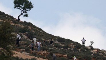 مستوطنون إسرائيليون مسلّحون فوق تلة تشرف على قرية المغير بالقرب من رام الله، في الضفة الغربية المحتلة (13 نيسان 2024 - أ ف ب).