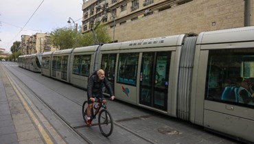 رجل يمر بدراجته بجانب قطار في القدس (14 نيسان 2024، أ ف ب). 