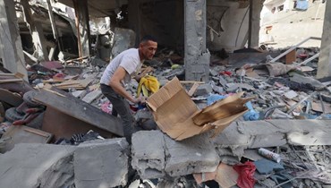 رجل فلسطيني يبحث في أنقاض مبنى دمره القصف الإسرائيلي خلال الليل في رفح بجنوب قطاع غزة (25 نيسان 2024، أ ف ب). 