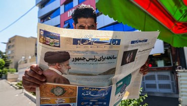 مواطن إيراني يتابعة تفاصيل حادث مقتل رئيس البلاد (أ.ف.ب)